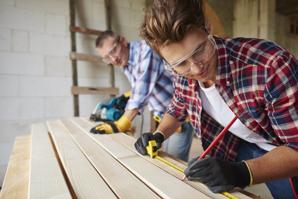 Younger carpenter is helping the older one